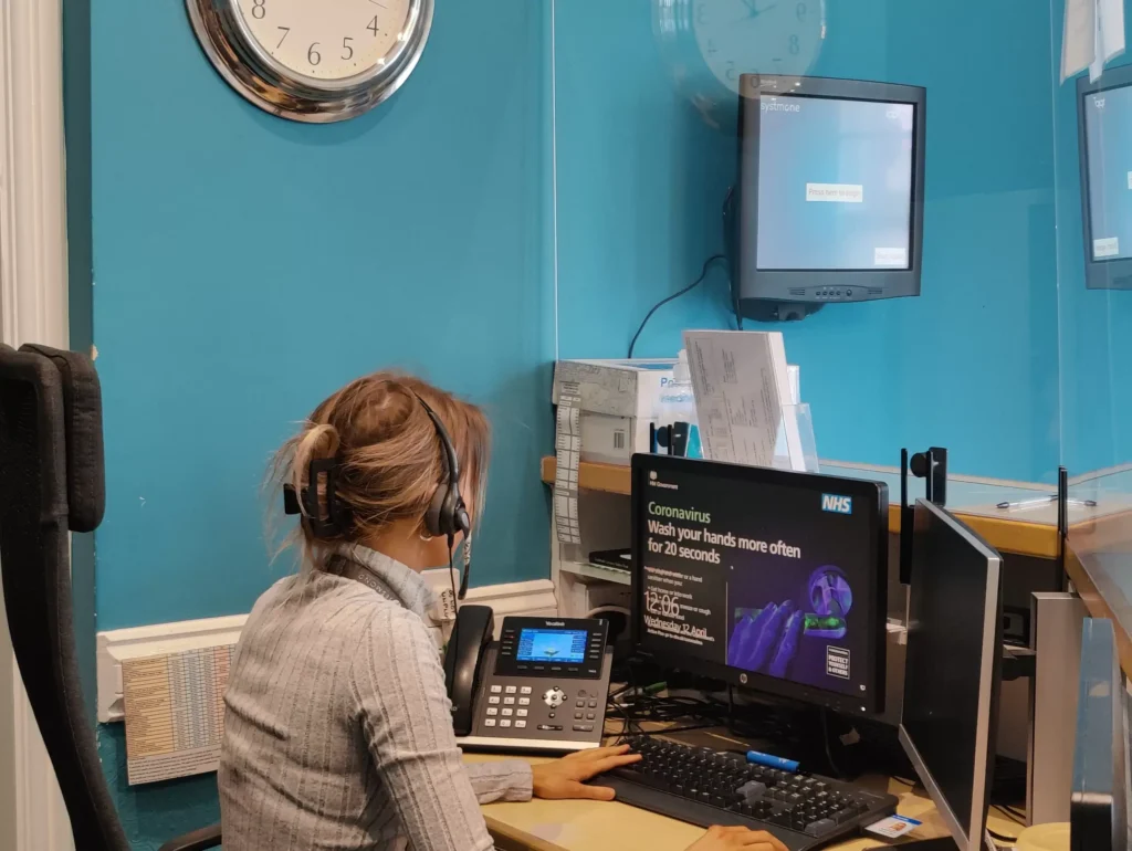 Woman working at a healthcare call centre with multiple screens and a headset.