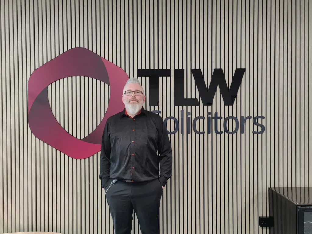 Man standing in front of TLW Solicitors logo at Smart IT office.