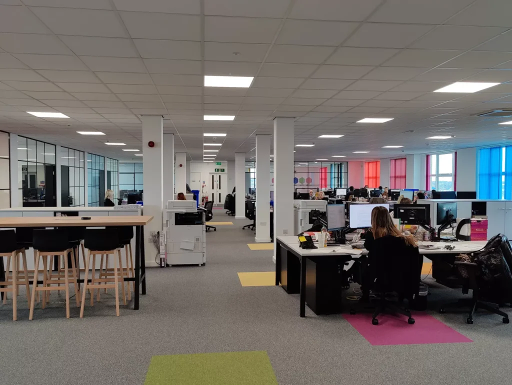 Open-plan office with desks, computers, and employees working.