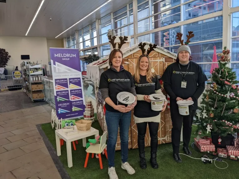 Smart IT team volunteering at Christmas charity event with festive decorations.