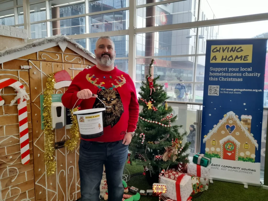 Man in Christmas jumper donating to local homelessness charity.