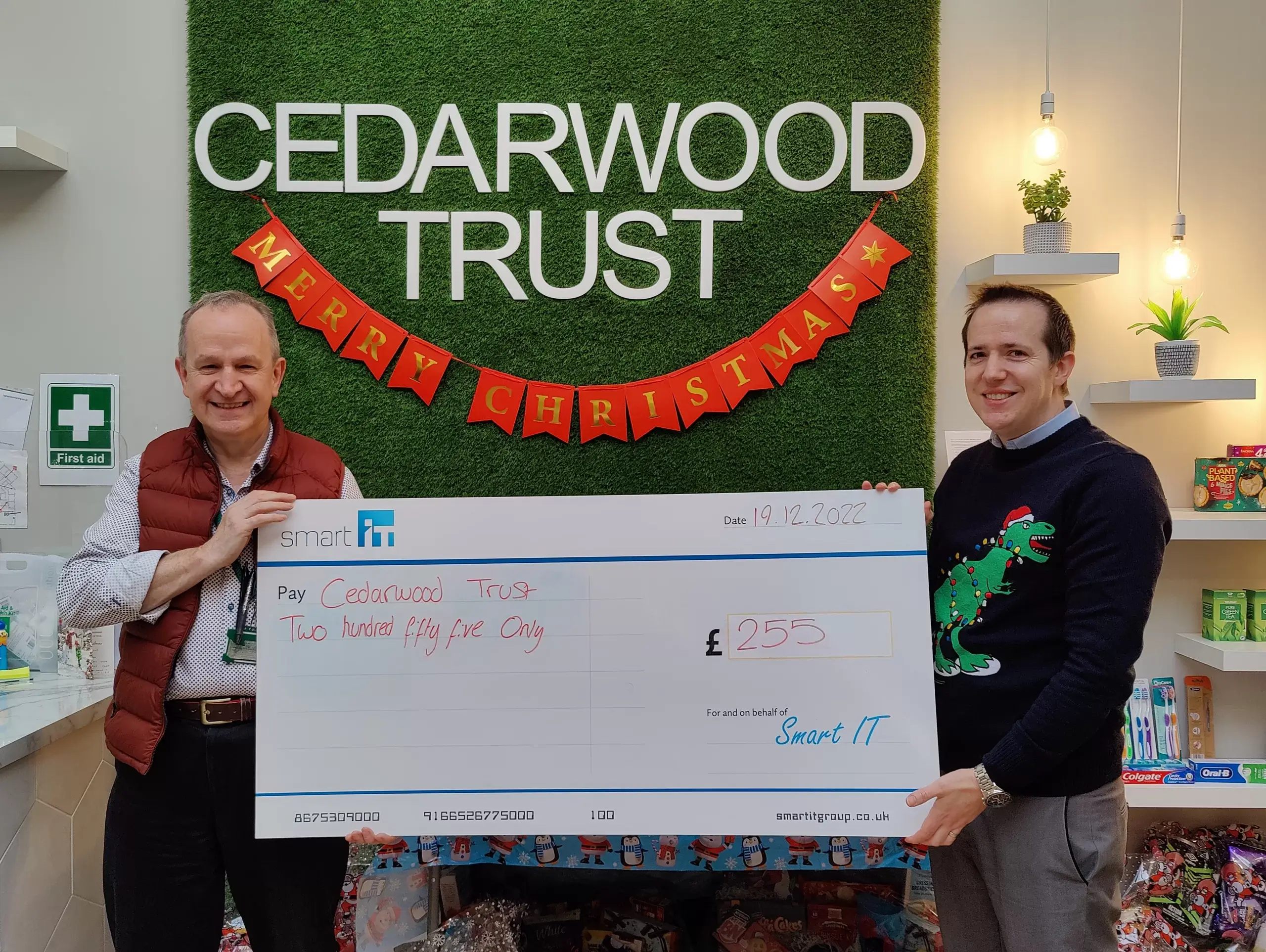 Two men holding a large cheque for charity donation at Cedarwood Trust.