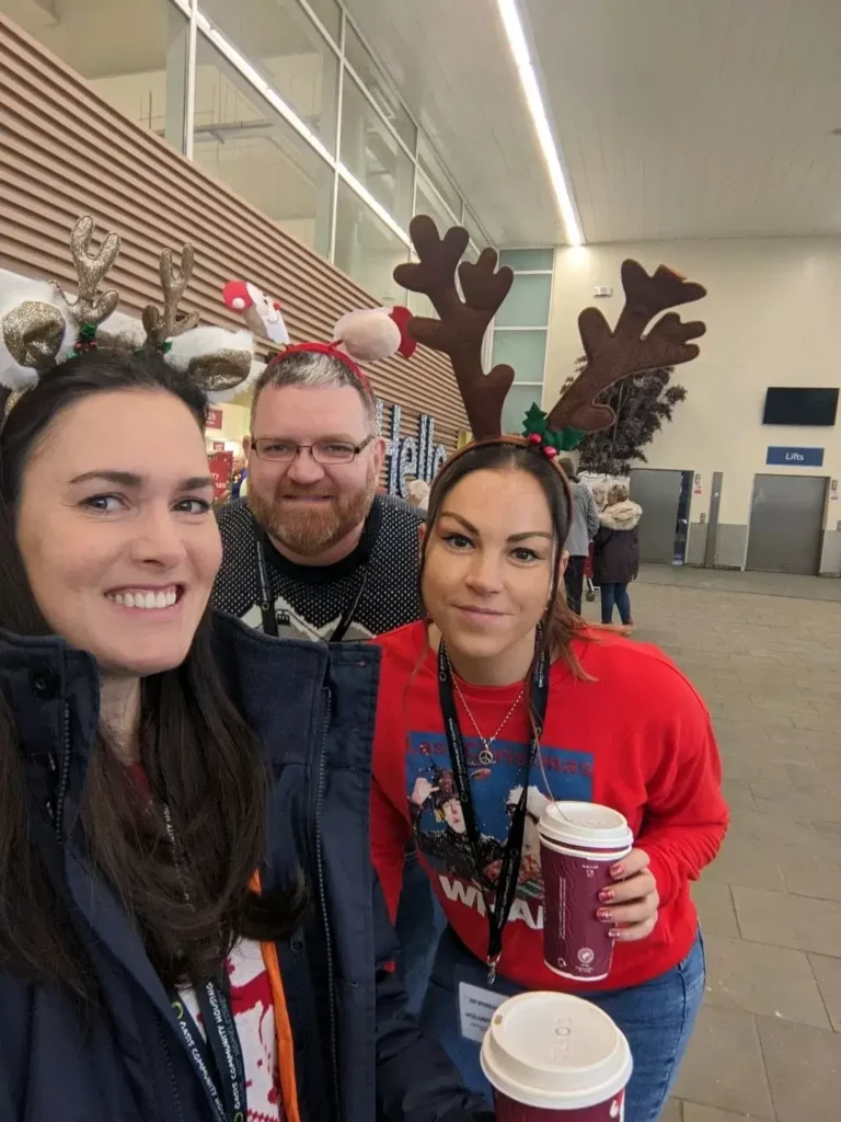 Group of volunteers wearing reindeer antlers at Christmas event.