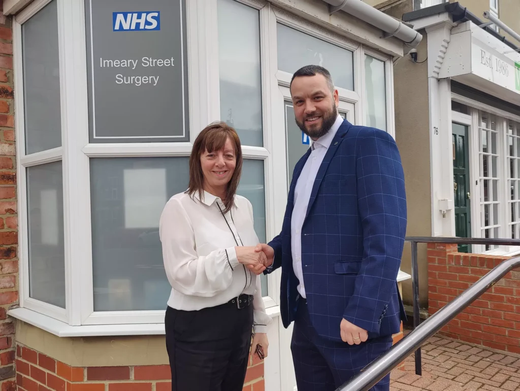 Business professionals shaking hands outside Imeary Street Surgery.