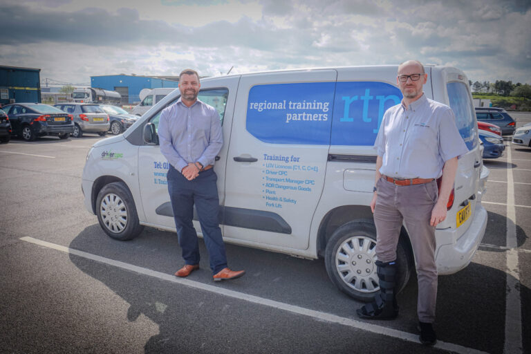 Two men standing beside a Regional Training Partners van in a parking lot.