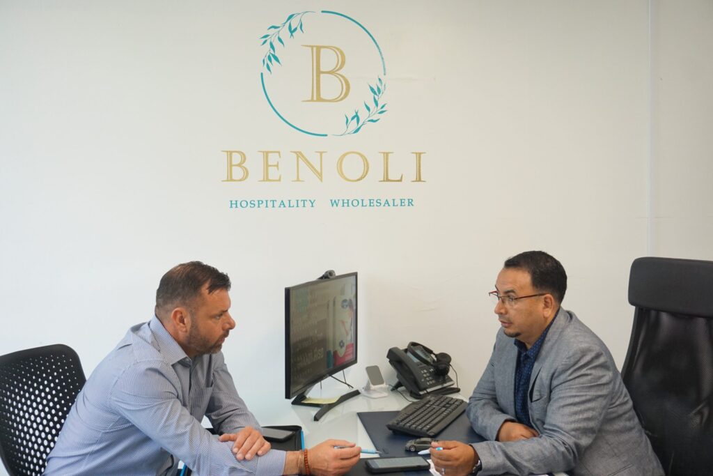 Two men in business suits having a discussion at an office desk.