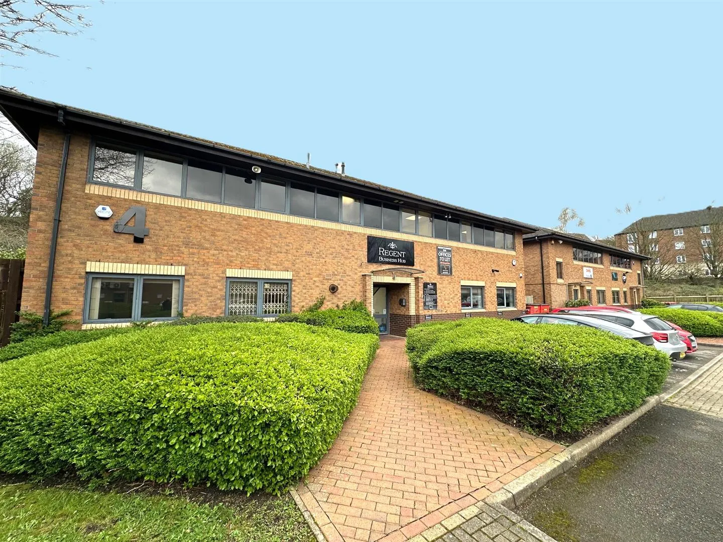 Contact Us 2 Modern office building with brick facade and parking lot in front.