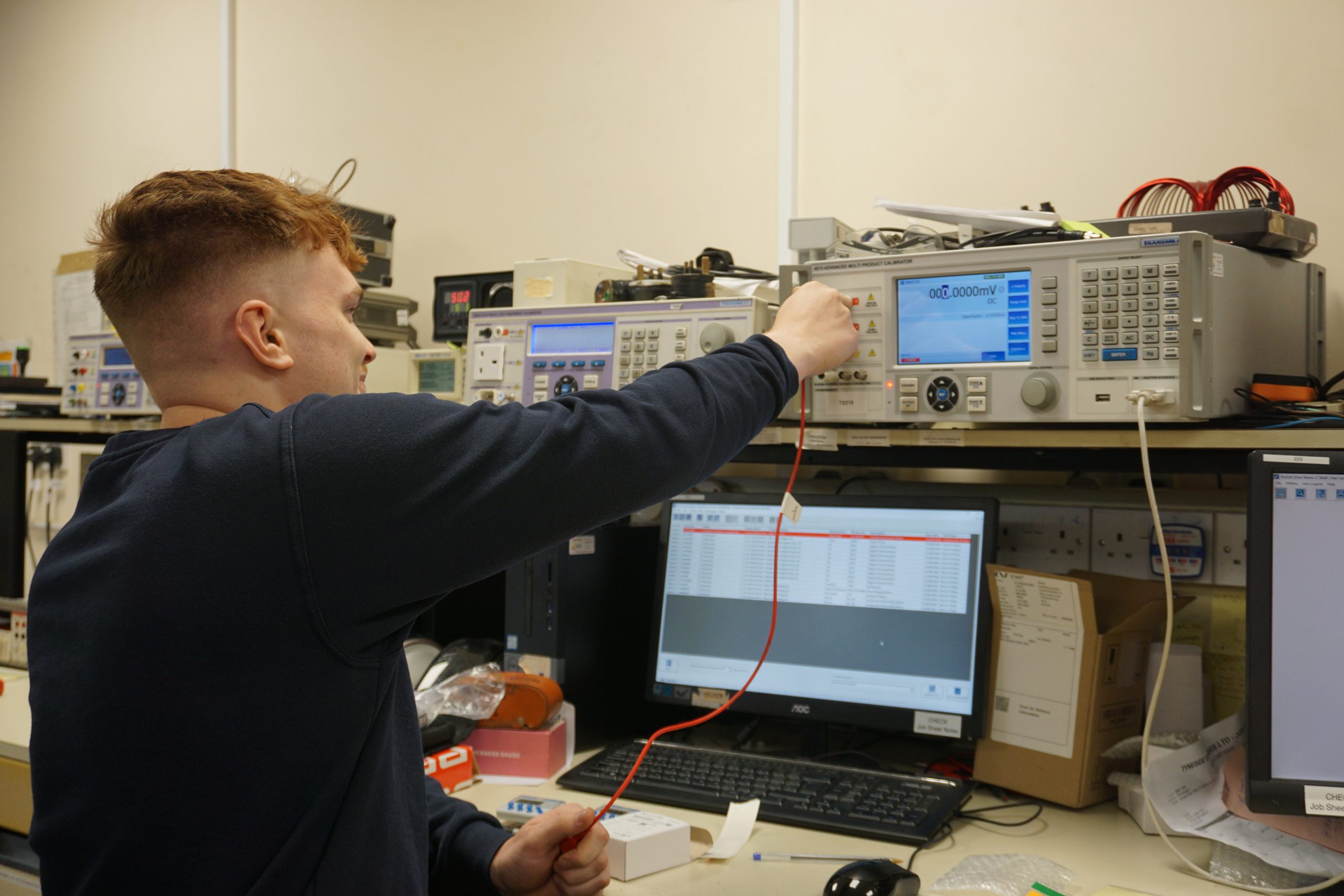 Young technician working with electronic testing equipment in lab.