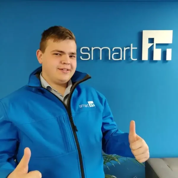 Young man in Smart IT jacket giving thumbs up in office.